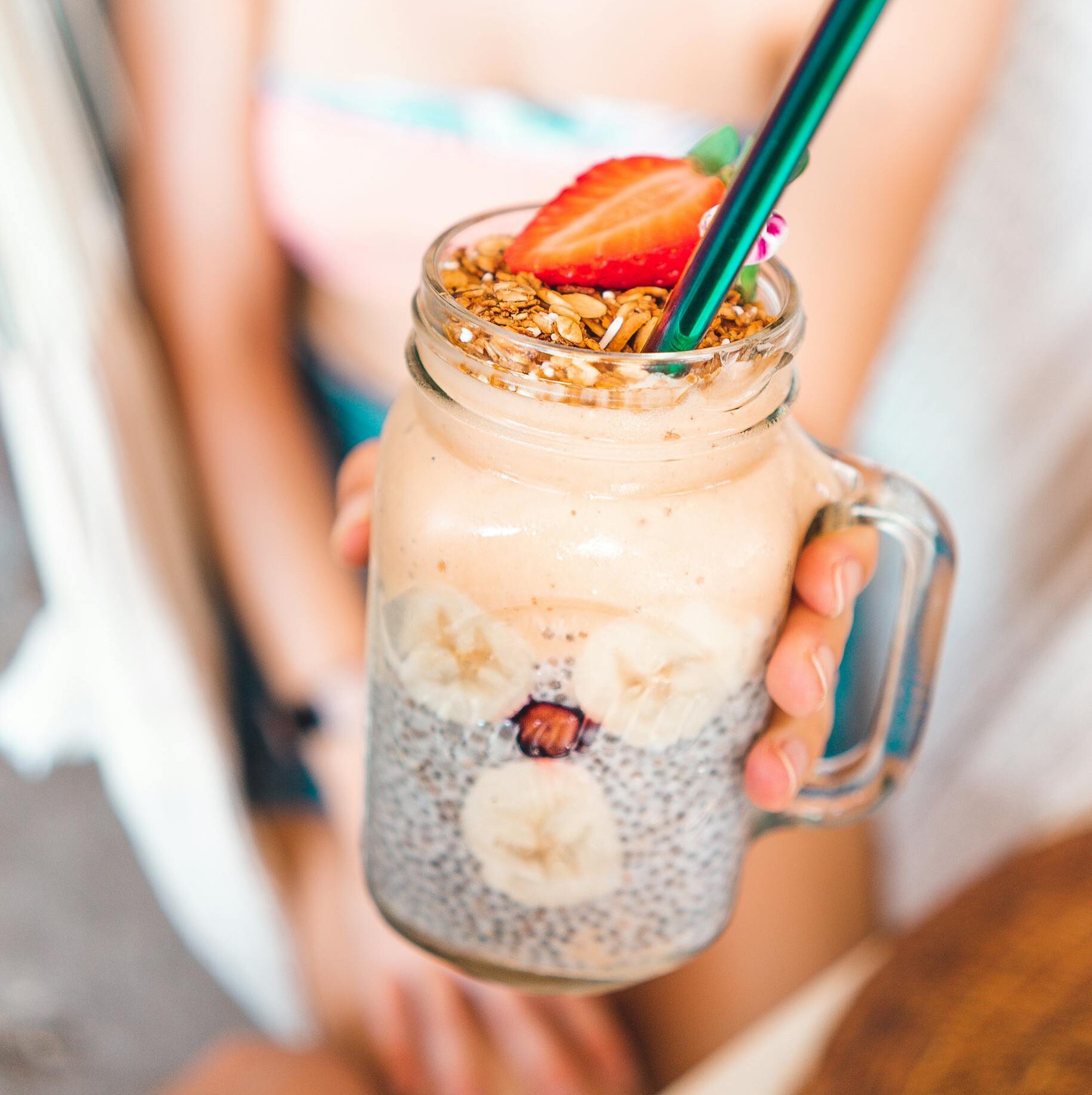 Delicious and fresh summer smoothie in a mason jar, topped with strawberries and granola.